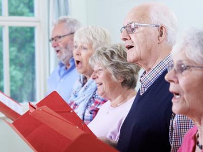 Billedet forestiller to ældre mænd og tre ældre kvinder, der synger, mens de holder sangbøger i hænderne.